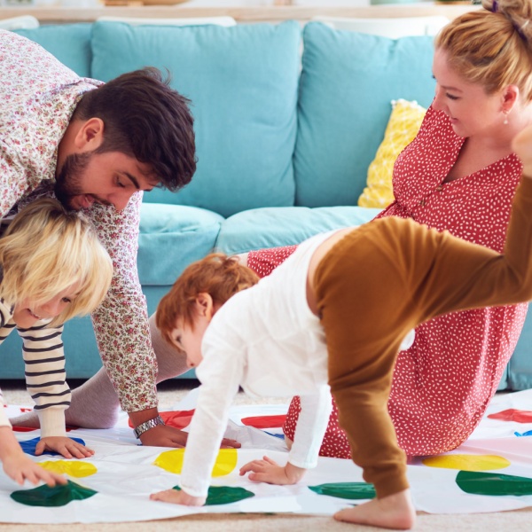 A family with young children playing Twister.