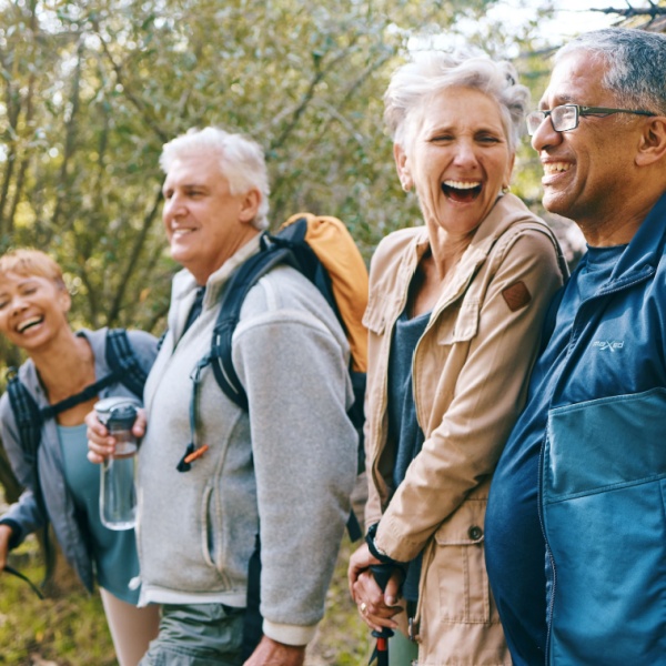 Four older people laughing and hiking together